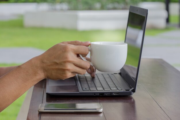 A close-up of a person's hands typing on a laptop, with a visible chat window in English and a coffee cup nearby. Natural lighting, emphasizing the focus and dedication to work.