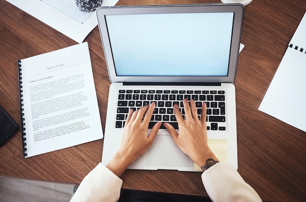 A hand typing on a laptop keyboard with a resume template visible on the screen in the background.