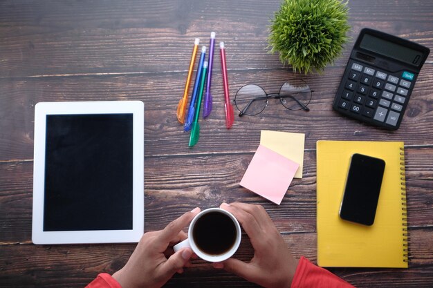 A person setting up reminders and due dates in a task management app on a tablet. There's a coffee cup and a plant on the desk, suggesting a comfortable and productive work atmosphere.