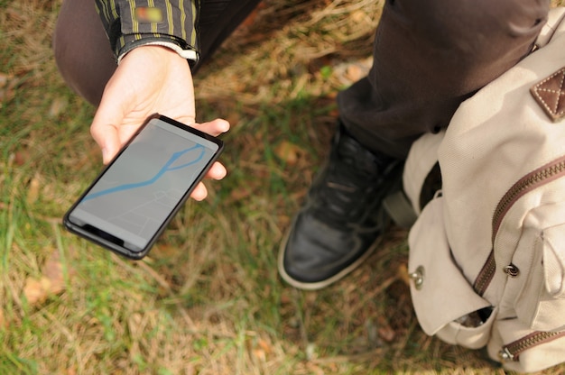 A person hiking in a remote area, using a smartphone with an offline map application to navigate, highlighting the importance of offline map functionality in areas with limited or no internet connectivity.