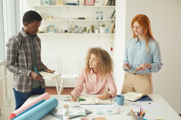 A parent filling out a form at a desk while discussing the childcare options with a staff member in an office environment.
