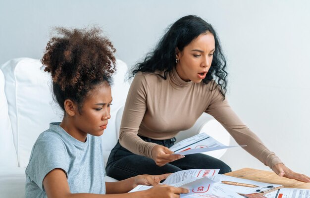 A concerned mother looking at a school report with low attendance marks, symbolizing challenges and the importance of addressing educational issues promptly.