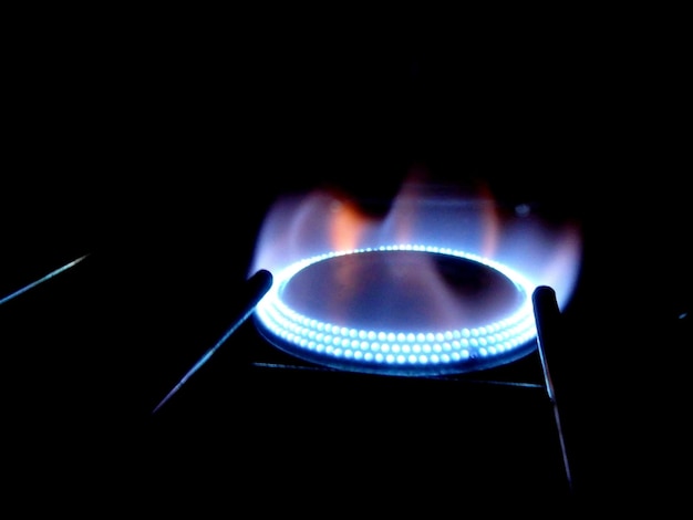 A close-up image of a gas stove burner with a blue flame, symbolizing the resource provided by the Vale-Gás program. Focus on the flame's clarity and intensity, with a blurred background.