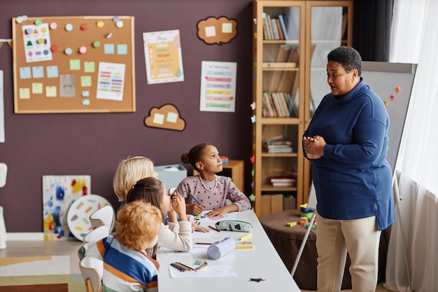 A classroom scene with children actively participating in a lesson with a teacher, symbolizing the importance of education for the future generation and highlighting the Bolsa Família's goal of promoting education among low-income families.