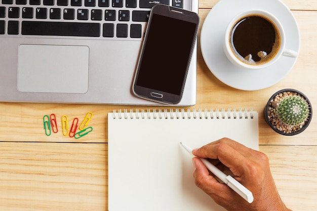 A person sitting at a desk, filling out an INSS registration form online on their laptop. A cup of coffee and a pen are also on the table.
