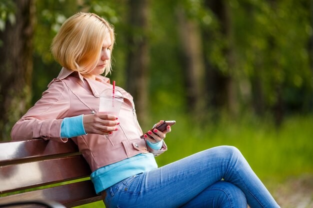 A person using a retirement planning calculator app on their phone, sitting in a park.
