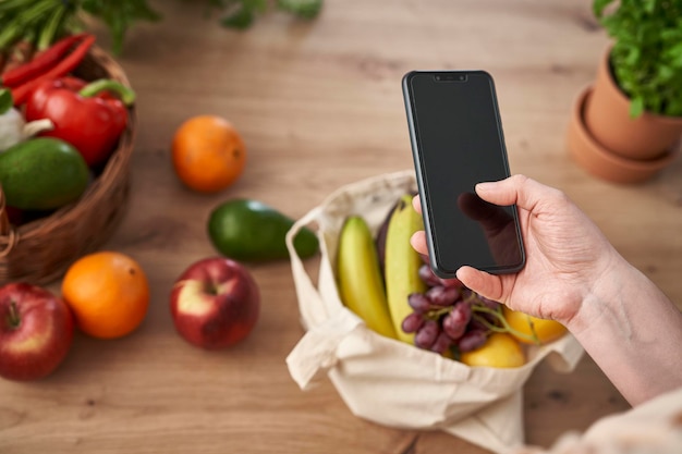 A close-up photo of a person using a smartphone to scan a QR code at a farmer's market, with a focus on fresh produce and sustainable packaging visible in the background.